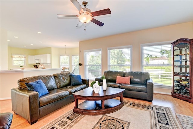 living room featuring a wealth of natural light, light hardwood / wood-style flooring, and ceiling fan