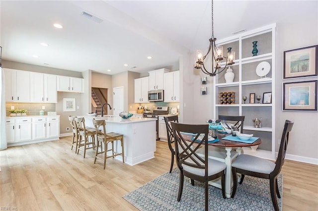 dining space with sink, a notable chandelier, and light hardwood / wood-style flooring