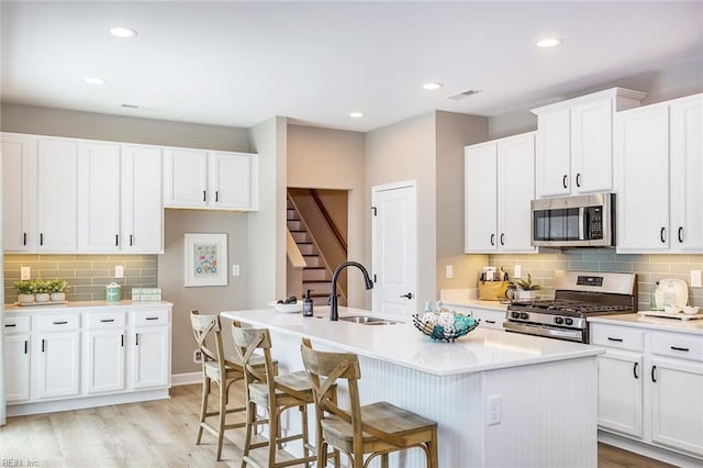 kitchen featuring appliances with stainless steel finishes, a kitchen island with sink, light hardwood / wood-style floors, and sink