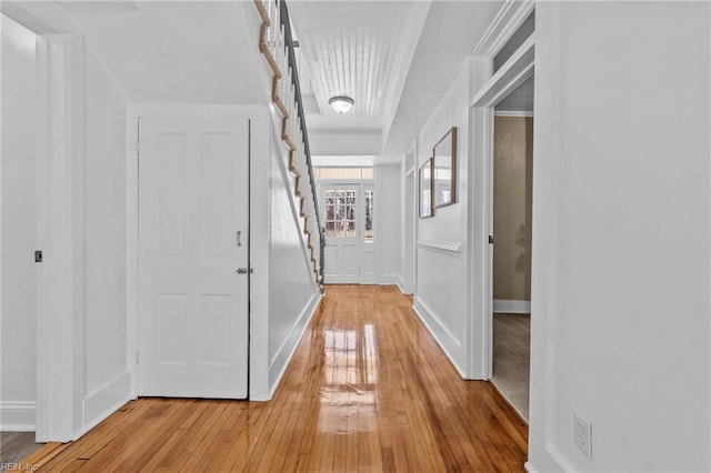 hall featuring light wood-type flooring, stairs, and baseboards