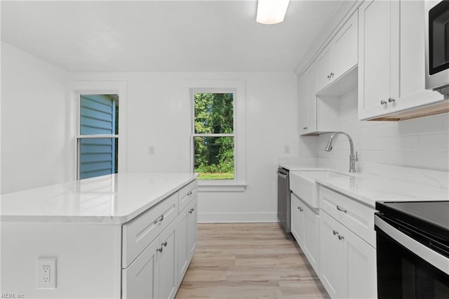 kitchen featuring white cabinetry, sink, backsplash, light wood-type flooring, and appliances with stainless steel finishes