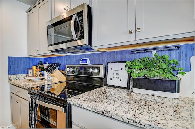 kitchen featuring gray cabinetry, light stone counters, and range with electric cooktop