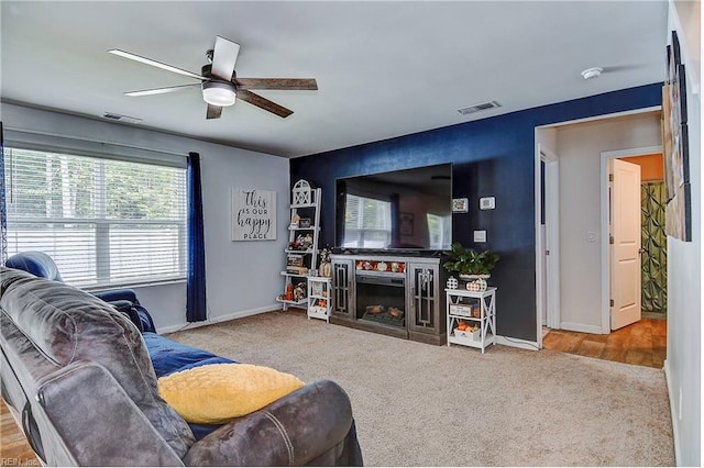 carpeted living room with ceiling fan and a fireplace