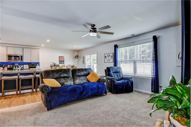 carpeted living room with ceiling fan