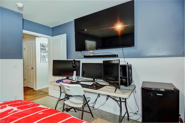 bedroom with baseboards, wood finished floors, and refrigerator