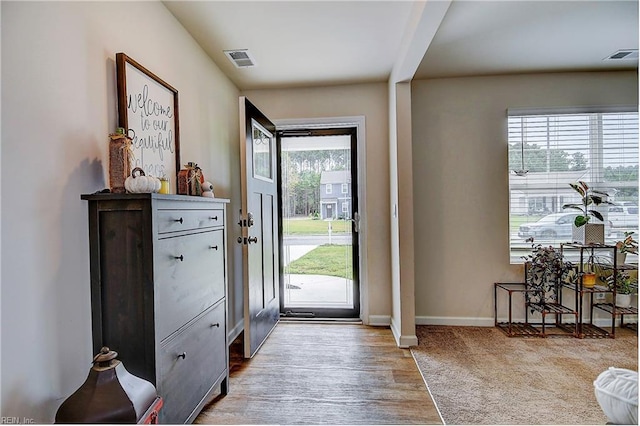 doorway to outside featuring baseboards, visible vents, and light wood-style flooring