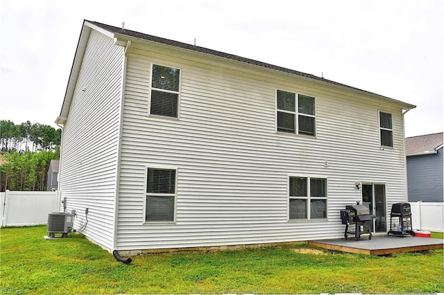 rear view of property with central AC and a lawn