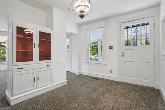 carpeted entryway with a notable chandelier