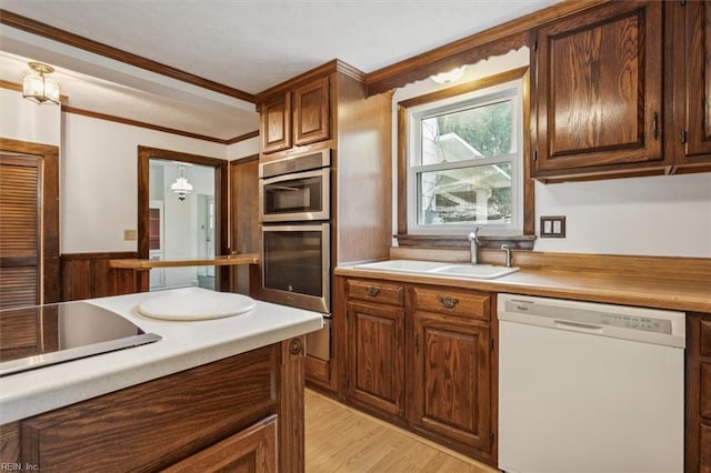 kitchen featuring sink, ornamental molding, double oven, light hardwood / wood-style flooring, and white dishwasher