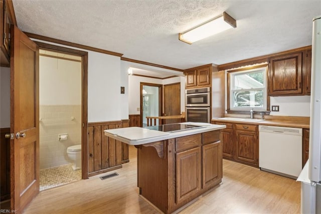 kitchen featuring double oven, a center island, light wood-type flooring, and white dishwasher