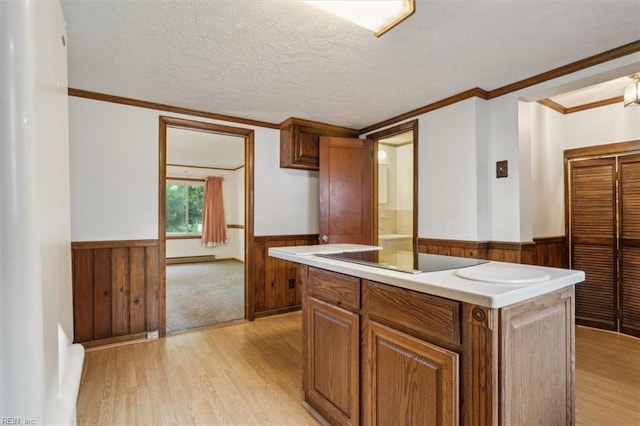 kitchen featuring light hardwood / wood-style floors, crown molding, a textured ceiling, and a kitchen island