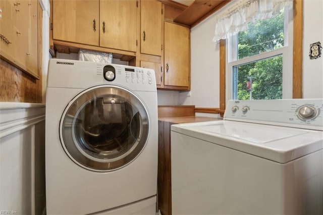 clothes washing area featuring cabinets and separate washer and dryer