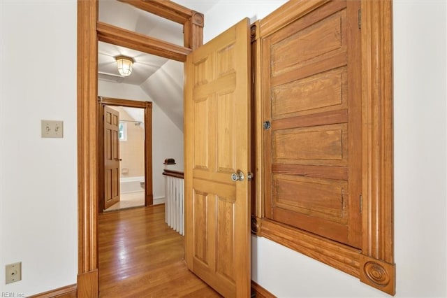 hall with vaulted ceiling and wood-type flooring