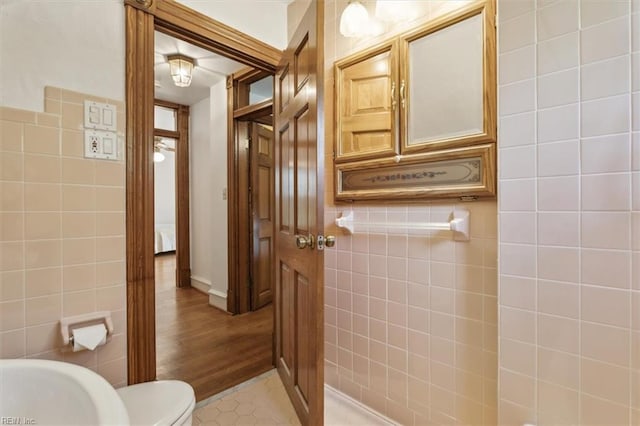 bathroom with tile walls, hardwood / wood-style floors, and toilet