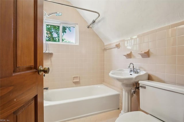 bathroom featuring tiled shower / bath, toilet, tile walls, and lofted ceiling