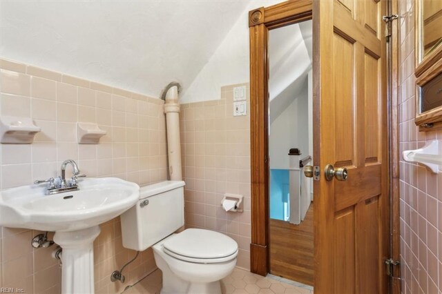 bathroom featuring toilet, decorative backsplash, tile patterned flooring, and tile walls