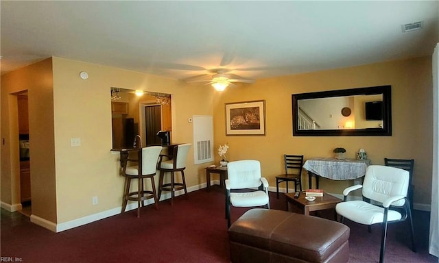 living area with dark carpet and ceiling fan