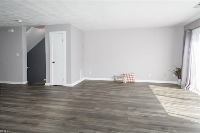 empty room with baseboards, visible vents, and wood finished floors