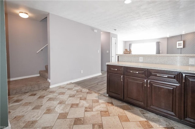 kitchen featuring baseboards and dark brown cabinets