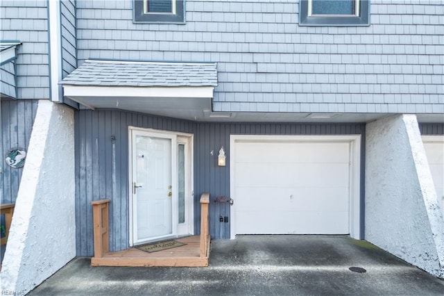 doorway to property with a shingled roof and an attached garage