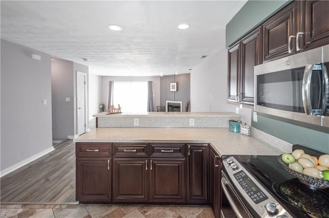 kitchen featuring stainless steel appliances, a peninsula, dark brown cabinetry, and recessed lighting