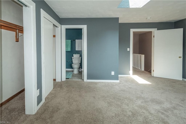 unfurnished bedroom with connected bathroom, baseboards, and carpet flooring