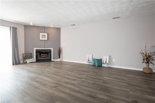 unfurnished living room featuring baseboards, a fireplace, visible vents, and wood finished floors