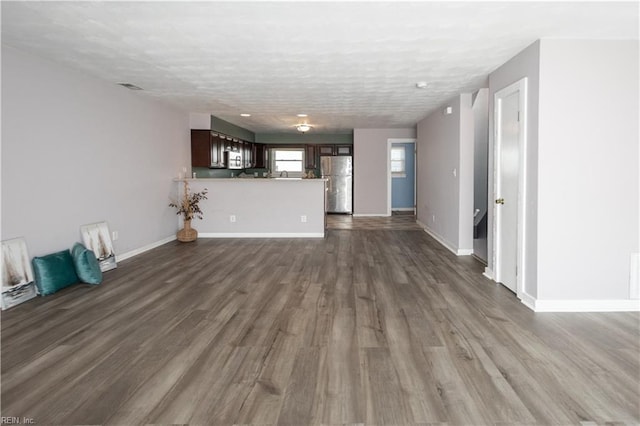 unfurnished living room featuring dark wood finished floors, a textured ceiling, and baseboards