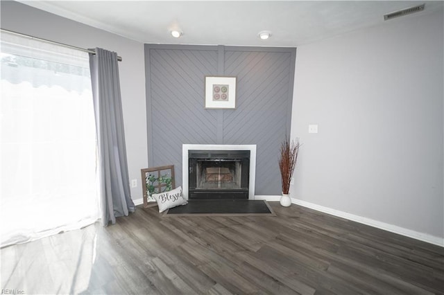 unfurnished living room with a large fireplace, wood finished floors, visible vents, and baseboards