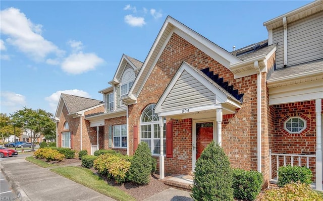 view of front of house featuring brick siding and roof with shingles