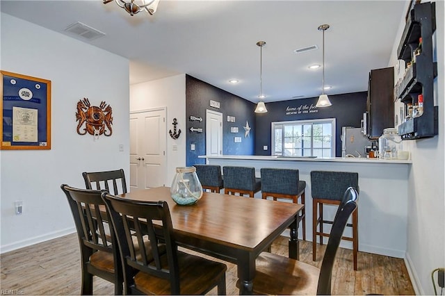 dining room featuring baseboards, visible vents, wood finished floors, and recessed lighting