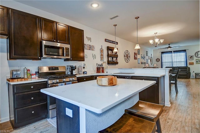 kitchen featuring light countertops, appliances with stainless steel finishes, open floor plan, a kitchen island, and a peninsula