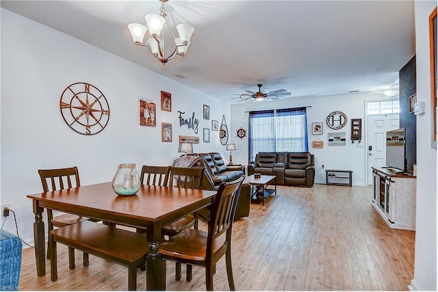 dining space with light wood-style flooring, visible vents, a wealth of natural light, and ceiling fan with notable chandelier