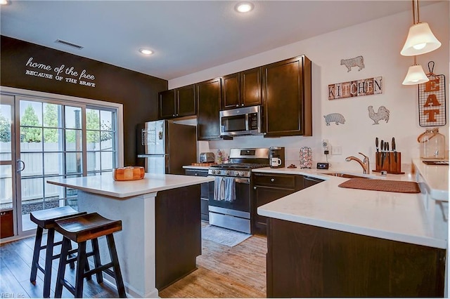 kitchen featuring a breakfast bar, light countertops, visible vents, appliances with stainless steel finishes, and dark brown cabinetry