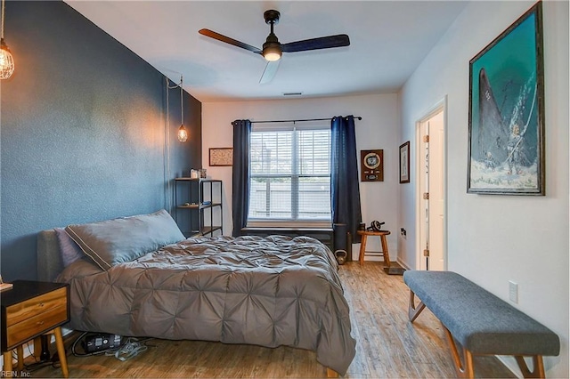 bedroom featuring wood finished floors, visible vents, and a ceiling fan