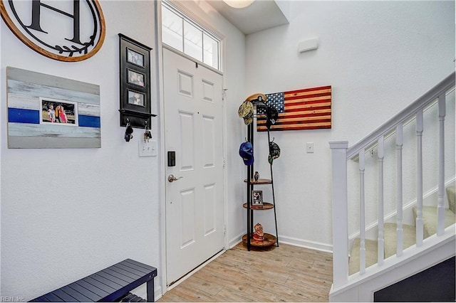 foyer with stairway, baseboards, and wood finished floors