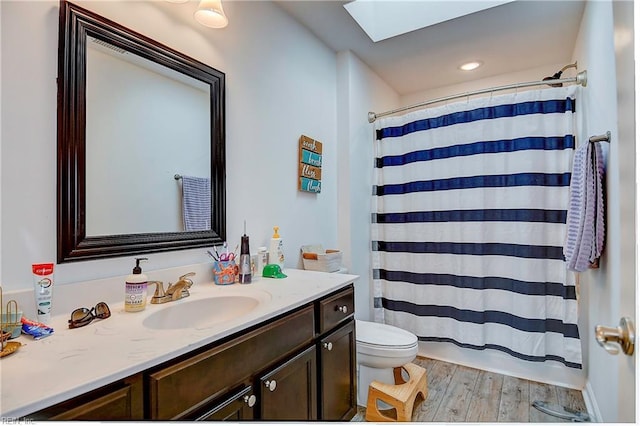 full bath with toilet, a shower with shower curtain, a skylight, vanity, and wood finished floors