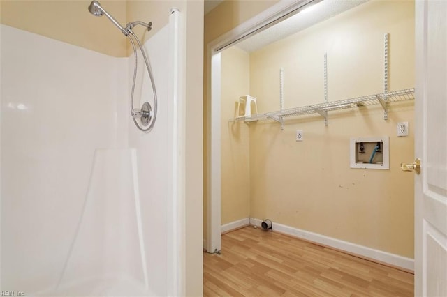 washroom with laundry area, hookup for a washing machine, baseboards, and wood finished floors