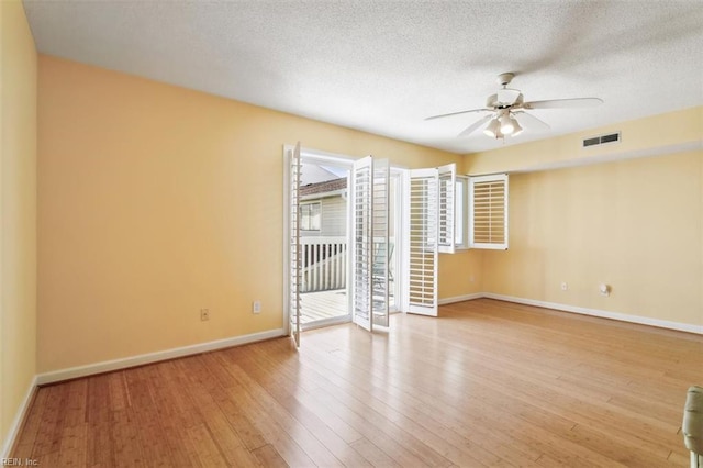 empty room with visible vents, baseboards, a textured ceiling, a ceiling fan, and wood-type flooring