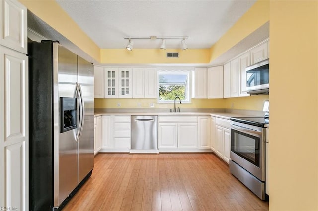 kitchen featuring light wood-type flooring, visible vents, a sink, white cabinetry, and appliances with stainless steel finishes