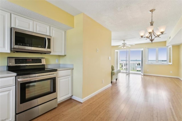 kitchen with light wood-type flooring, a textured ceiling, open floor plan, stainless steel appliances, and white cabinets