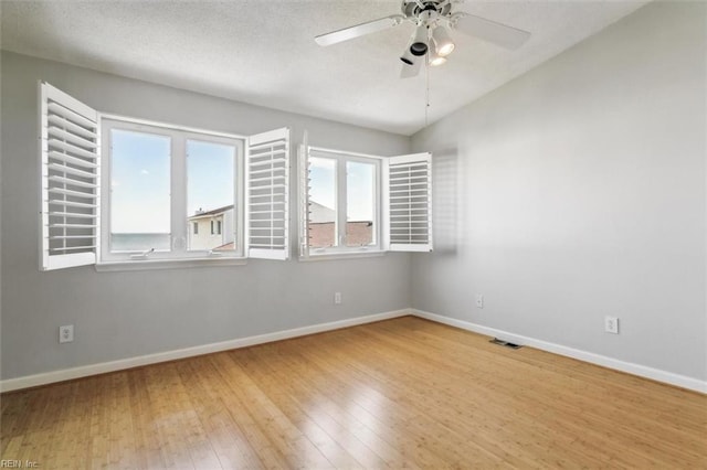 empty room featuring hardwood / wood-style floors, baseboards, visible vents, and ceiling fan