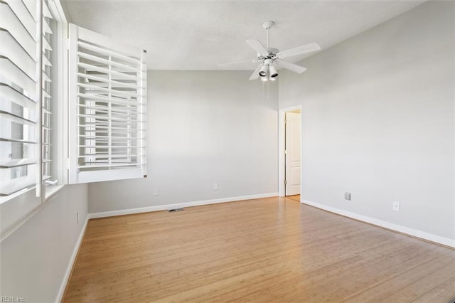 unfurnished room featuring visible vents, baseboards, vaulted ceiling, wood finished floors, and a ceiling fan