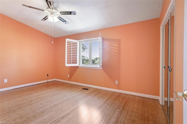 spare room with visible vents, a textured ceiling, wood finished floors, baseboards, and ceiling fan