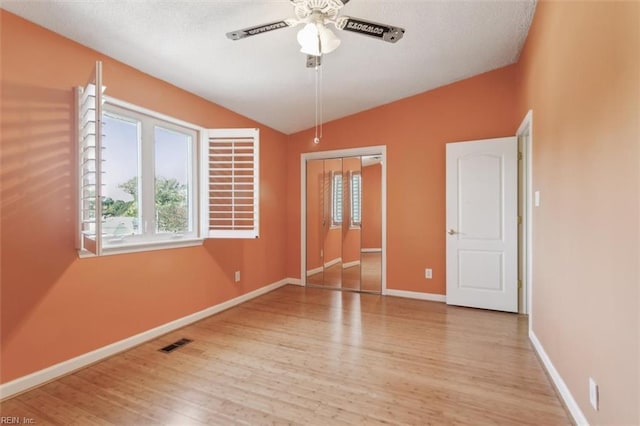 unfurnished bedroom featuring visible vents, baseboards, lofted ceiling, wood finished floors, and a closet