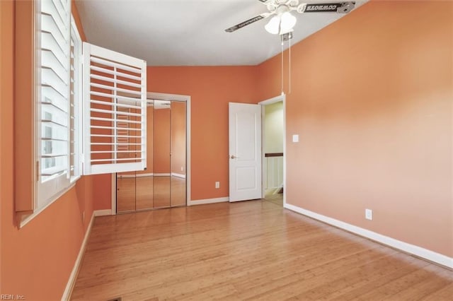 unfurnished bedroom with wood finished floors, a closet, and baseboards