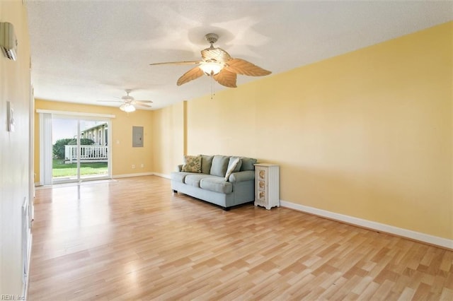 unfurnished room featuring electric panel, a textured ceiling, light wood finished floors, baseboards, and ceiling fan