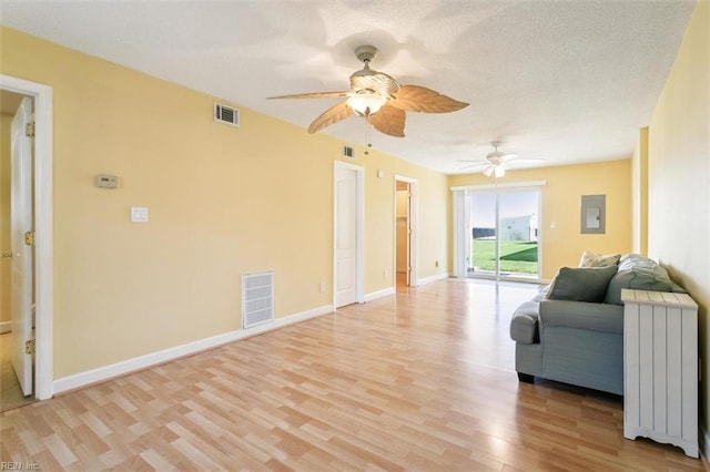 living room with visible vents, baseboards, radiator heating unit, and light wood-style floors