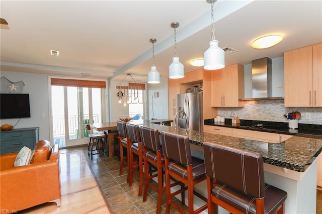 kitchen featuring decorative light fixtures, stainless steel fridge, light brown cabinets, and a breakfast bar