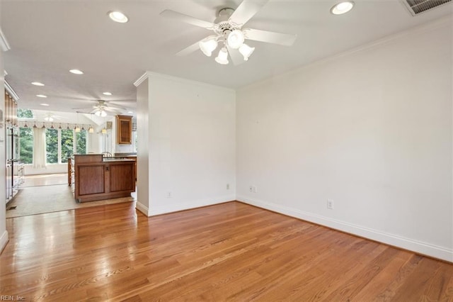 unfurnished living room with visible vents, crown molding, light wood-type flooring, and baseboards